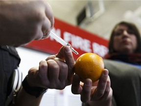 Edmonton Fire Rescue Services Training Officer Clint Snider (left) demonstrates how a naloxone kit works with an orange as the government of Alberta announces greater access to lifesaving naloxone kits at Edmonton Fire Rescue Services Fire Station No. 1 in Edmonton on Tuesday, Feb. 7, 2017.