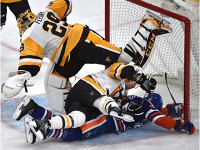 Edmonton Oilers Matt Hendricks (23) is taken down by Pittsburgh Penguins Tom Kuhnhackl (34) as goalie Marc-Andre Fleury (29) gets out of the way during third period NHL action at Rogers Place in Edmonton, Saturday, March 10, 2017.