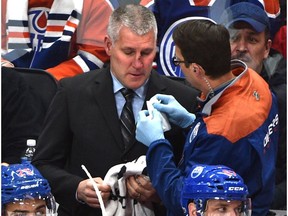 An Edmonton Oilers trainer tends to assistant coach Jim Johnson after getting hit by the puck against the Montreal Canadiens at Rogers Place on Sunday, March 12, 2017. (Ed Kaiser)