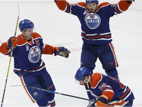 Edmonton Oilers forward Patrick Maroon, bottom right, celebrates a goal with linemates Connor McDavid, left, and Leon Draisaitl against the New Jersey Devils on Jan. 12, 2017.