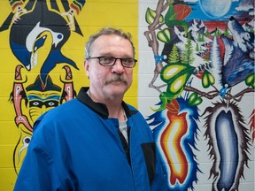Charles Bastien poses for a photo with a mural he painted at the Fort Saskatchewan Correctional Centre in Fort Saskatchewan, Alta. on October 15, 2014.