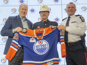 Kevin Lowe, left, of the Oilers Entertainment Group presents a special Oilers jersey with EPS shoulder flashes and a 125 shoulder patch to Police Chief Rod Knecht. In the middle is Dave Hawthorne of the EPS Historical Unit.
