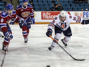 Kamloops Blazers centre Lane Bauer reaches for the puck against Edmonton Oil Kings defencemen Ethan Cap, left, and Conner McDonald at the Sandman Centre in Kamloops, B.C., on Feb. 21, 2017.