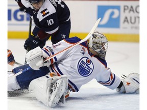 Edmonton Oilers goalie Laurent Brossoit, front, makes a backhanded glove save of a shot by Colorado Avalanche right wing Sven Andrighetto, back right, as Oilers right wing Jordan Eberle defends during NHL action on March 23, 2017, in Denver.