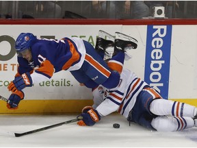 New York Islanders center Shane Prince (11) trips over Edmonton Oilers left-winger Milan Lucic on Nov. 5, 2016, in New York. The Oilers won 4-3 in a shootout. (AP Photo)