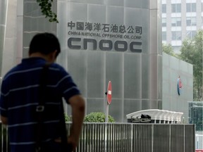 A man stands outside the headquarters building of China National Offshore Oil Corporation (CNOOC) in Beijing on July 29, 2016.