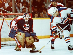 WInnipeg Jets goalie stands ready as defenceman Peter Taglianetti and Edmonton Oilers forward Craig Simpson reach for the puck during Game 2 of their Smythe Division semifinal playoff series April 7, 1988, at Northlands Coliseum.