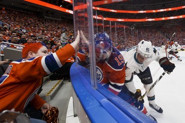 A fan pounds on the glass as Edmonton's Patrick Maroon (19) battles San Jose's Justin Braun (61) during the third period of a Stanley Cup playoffs game between the Edmonton Oilers and the San Jose Sharks at Rogers Place in Edmonton on Wednesday, April 12, 2017.