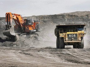 A haul truck carrying a full load drives away from a mining shovel at the Shell Albian Sands oilsands mine near Fort McMurray, Alta. File photo.