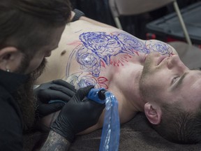 Chris Rhyason of Sterling Skull studio in Grande Prairie inks Beau Sheane at the Edmonton Expo Centre. The Edmonton Tattoo and Arts show featured over 250 exhibitors live entertainment on April 1, 2017.
