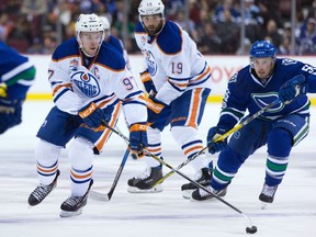 Edmonton Oilers' Connor McDavid (97) skates with the puck while being chased by Vancouver Canucks' Alex Biega (55) during first period NHL hockey action in Vancouver, B.C., on Saturday, April 8, 2017.