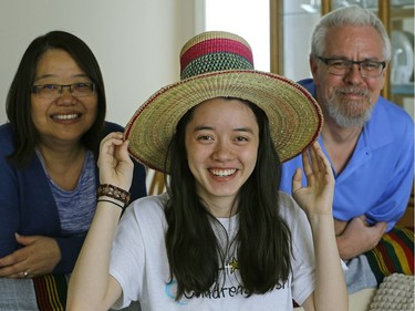 Isabel Schuppli (18-years-old) tries on a traditional Ethiopian tribal hat that she picked up recently from a family trip to Ethiopia. Beside her is her mother Julia Lee-Schuppli (left) and father James Schuppli (right) at their home in Edmonton. Isabel was diagnosed with cancer in 2015 and used her Children's Wish Foundation wish to travel to Ethiopia to visit the girl that her family sponsors through Compassion Canada. (PHOTO BY