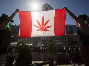 Two people hold a modified design of the Canadian flag with a marijuana leaf in place of the Maple Leaf during the 420 Toronto rally in Toronto on April 20, 2016.