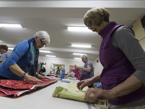 Grandmothers of Alberta for a New Generation members Louise Barr (left) and Colleen Kennedy fold fabric for a sale on April 22. Proceeds go towards charitable programs for grandmothers in sub-Saharan Africa.