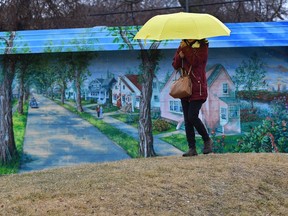 Spring showers, mixed with snow, gives way to greeny as a woman (no name given) walks by a summertime mural along 103 Ave. near 114 St. in Edmonton, Thursday, April 13, 2017. Ed Kaiser/Postmedia (Standalone Photo)