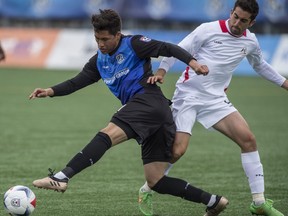 Dustin Corea of FC Edmonton, is slowed by Tyler Gibson of the San Francisco Deltas at Clark Stadium in Edmonton on May 14, 2017.