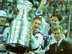Edmonton Oilers captain Wayne Gretzky, centre, holds the Stanley Cup alongside alternate captains Mark Messier, left, and Kevin Lowe, right, after receiving the trophy from NHL commissioner John Ziegler, bottom right, on May 26, 1988, after the Oilers beat the Boston Bruins 6-3 in Game 4 of the Stanley Cup final at Northlands Coliseum to win the league title.
