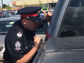 Acting Staff Sgt. Paul Looker with the Edmonton police looks through cars in the parking lot outside of Southgate Centre at 5015 111 St. on May 15, 2017. Looker joined volunteers from from Centre High's Emergency Response Careers Pathways program who handed out pamphlets and advice to car owners about how to keep their property safe as part of Crime Prevention Week.