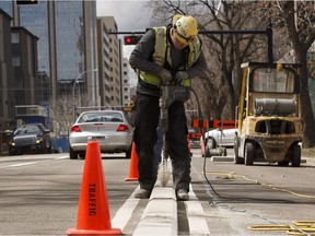 Brandon Black with Concrete Inc., works with his crew installing lanes for the permanent downtown bike lane system along 100 Avenue near 104 Street in Edmonton on Monday, May 1, 2017.