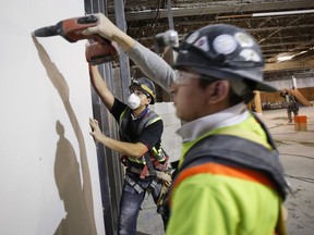 Construction workers install sheets of drywall at a building project in Calgary in late 2016.