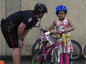 Cst. Liam Watson helps Hyab Gidey ,6, during the eighth Annual Bike Festival at the Edmonton Expo Centre Saturday. on Saturday May 27, 2017, in Edmonton.