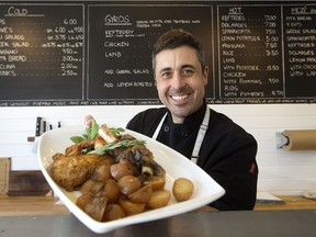 Little Village's Theo Psalios holds a plate of roast lamb, chicken and potatoes.