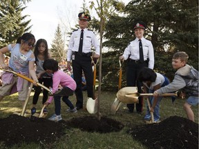 Edmonton police officers including Chief Rod Knecht, fourth from left, and Grade 1 students plant an autumn blaze maple tree for the 125th anniversary of the police service during Arbor Day festivities at Gold Bar Park in Edmonton on May 5, 2017.