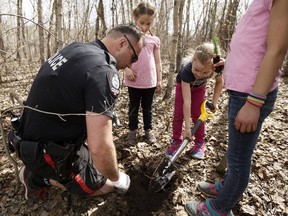 Edmonton police Const. Christopher Lucas was one of the officers who planted a tree with the Oak team of Grade 1 students from Parkland Immanuel Christian School during Arbor Day festivities at Gold Bar Park in Edmonton on May 5, 2017.