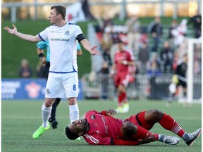 Edmonton FC captain Nick Ledgerwood tries to explain lack of fault to the ref as Ottawa FC's Eddie Edward writhes in pain after they tangled on the field in the first leg of the Canadian Championship at TD Place in Ottawa on Wednesday, May 3, 2017. (Julie Oliver)