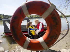 Framed by a life preserver, City of Edmonton aquatic program co-ordinator Debi Curry and Quinn Carter, 11, demonstrate the correct way to put on a lifejacket during a National Lifejacket Day event in Sir Wilfrid Laurier Park,  in Edmonton Thursday May 18, 2017.