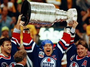 Edmonton Oilers' Kevin Lowe, Mark Messier (holding cup overhead) and Jari Kurri celebrate after winning the Stanley Cup on May 24, 1990.
