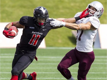Carleton Ravens receiver Nathaniel Behar straight-arms the Ottawa Gee-Gees' Mike Randazzo during CIS football action on Sept. 20, 2014.