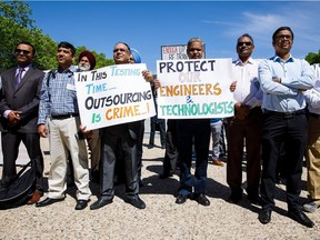 Protesters hold signs during a rally for unemployed energy workers at the Alberta legislature in Edmonton on Tuesday, May 30, 2017.