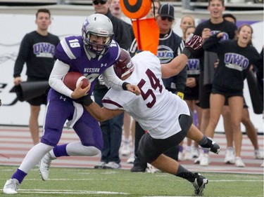 Western Mustangs backup quarterback Stevenson Bone is tackled by McMaster Marauders defensive lineman Mark Mackie during their OUA football game at TD Stadium in London, Ont., on Oct. 4, 2014.