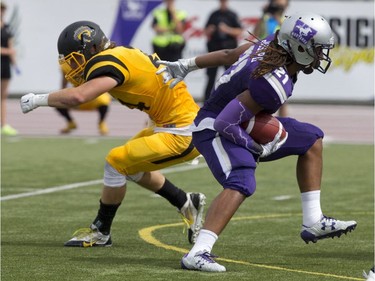 Western Mustangs running back Cedric Joseph, right, sidesteps his way around Waterloo Warriors defensive back Jordan Hoover during their OUA football game at TD Stadium in London, Ont., on Sept. 10, 2016.