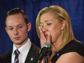 Shelly MacInnis-Wynn, the widow of Constable David Wynn, wipes tears as she responds to the Liberal's defeat of Bill S-217 known as Wynn's Law at Committee during a news conference as MP Michael Cooper looks on in St. Albert, May 12, 2017.