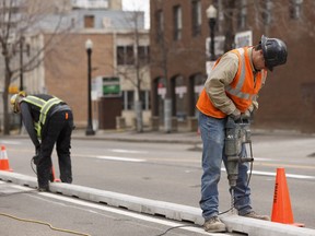 Workers install lanes for the new downtown bike lane network along 100 Avenue near 104 Street on May 1, 2017.