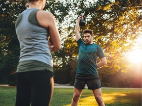 A man uses a kettlebell during a workout with a personal trainer.