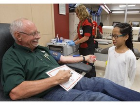 Hosanna Crowell, 11, visits Terry Allison as he makes his 100th blood donation at Canadian Blood Services, 8249  114 St., in Edmonton on Wednesday, June 14, 2017. Hosanna requires a transfusion every three weeks and is approaching her 200th transfusion.