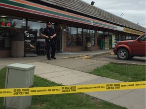 An Edmonton Police Service officer guards the 7-Eleven at 11868 145 Ave NW in Castle Downs Plaza beside glass shattered by gunfire on Sunday, June 11, 2017. Police responded to the gun complaint around 4:40 p.m. and found a man in life-threatening condition.