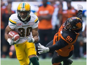 Edmonton Eskimos' John White, left, gets away from B.C. Lions' Mic'hael Brooks during the first half of a CFL football game in Vancouver, B.C., on Saturday, June 24, 2017.