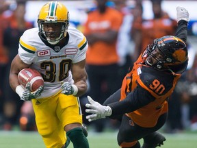 Edmonton Eskimos' John White, left, gets away from B.C. Lions' Mic'hael Brooks during the first half of a CFL football game in Vancouver on June 24, 2017.