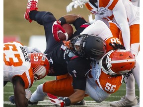 B.C. Lions' Alex Bazzie, left, Solomon Elimimian, right, and Anthony Gaitor, top right, bring down Calgary Stampeders' Lemar Durant during first half CFL western final action, in Calgary on Sunday, Nov. 20, 2016.
