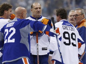 Former Edmonton Oilers Dave Semenko, centre, and others listen in as captain Wayne Gretzky (99) leads a huddle during a practice for the NHL's Heritage Classic Alumni game in Winnipeg on Friday, October 21, 2016. Semenko, the former NHL tough guy who served as Wayne Gretzky's bodyguard and once went three rounds with boxing legend Muhammad Ali, has died after a battle with cancer.