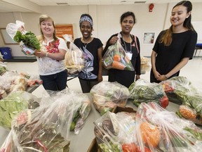 Volunteers and workers, including Liliya Bossniak, left, and Sandra Ngo, right, with Multicultural Health Brokers show their kits made for mothers in Edmonton's immigrant communities at Old McCauley School on Thursday, June 15, 2017.