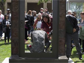 People lay flowers during the Edmonton Homeless Memorial at the memorial sculpture north of City Hall on Friday June 2, 2017, in Edmonton.