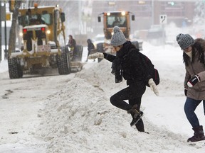 A pedestrian makes her way over a windrow left behind as graders cleared 102 Avenue in Edmonton last winter. Using liquid calcium chloride will mean graders will be able to plow down to bare pavement easier than previously.