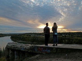 A couple watches the sun set along the North Saskatchewan River from The End of the World.