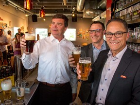 Agriculture Minister Oneil Carlier, left, Terry Rock of the Alberta Small Brewers Association and Finance Minister Joe Ceci toast new subsidies announced for small breweries at Village Brewery in Calgary on July 28, 2016. Ceci said Friday more changes are coming to Alberta's liquor laws.