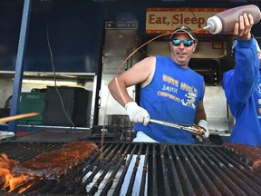 Jame Stoddart watches Jamie Breault squirt sauce onto his ribs barbecuing over a wood fire at Boss Hogs BBQ, one of the three rib vendors during Ribfest at K-Days in Edmonton, July 23, 2017. Ed Kaiser/Postmedia (Edmonton Journal story by Dustin Cook) For a Dustin Cook story running July 24, 2017.
Ed Kaiser